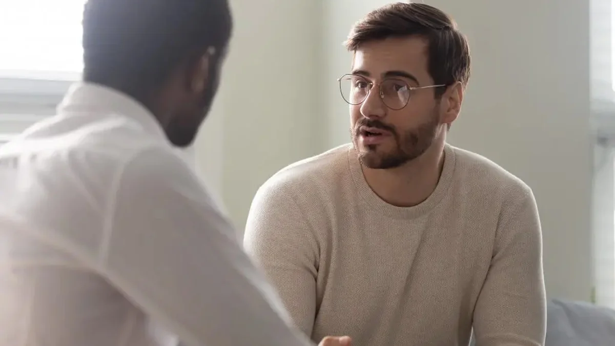 man looking at his therapist intently in a well lit room